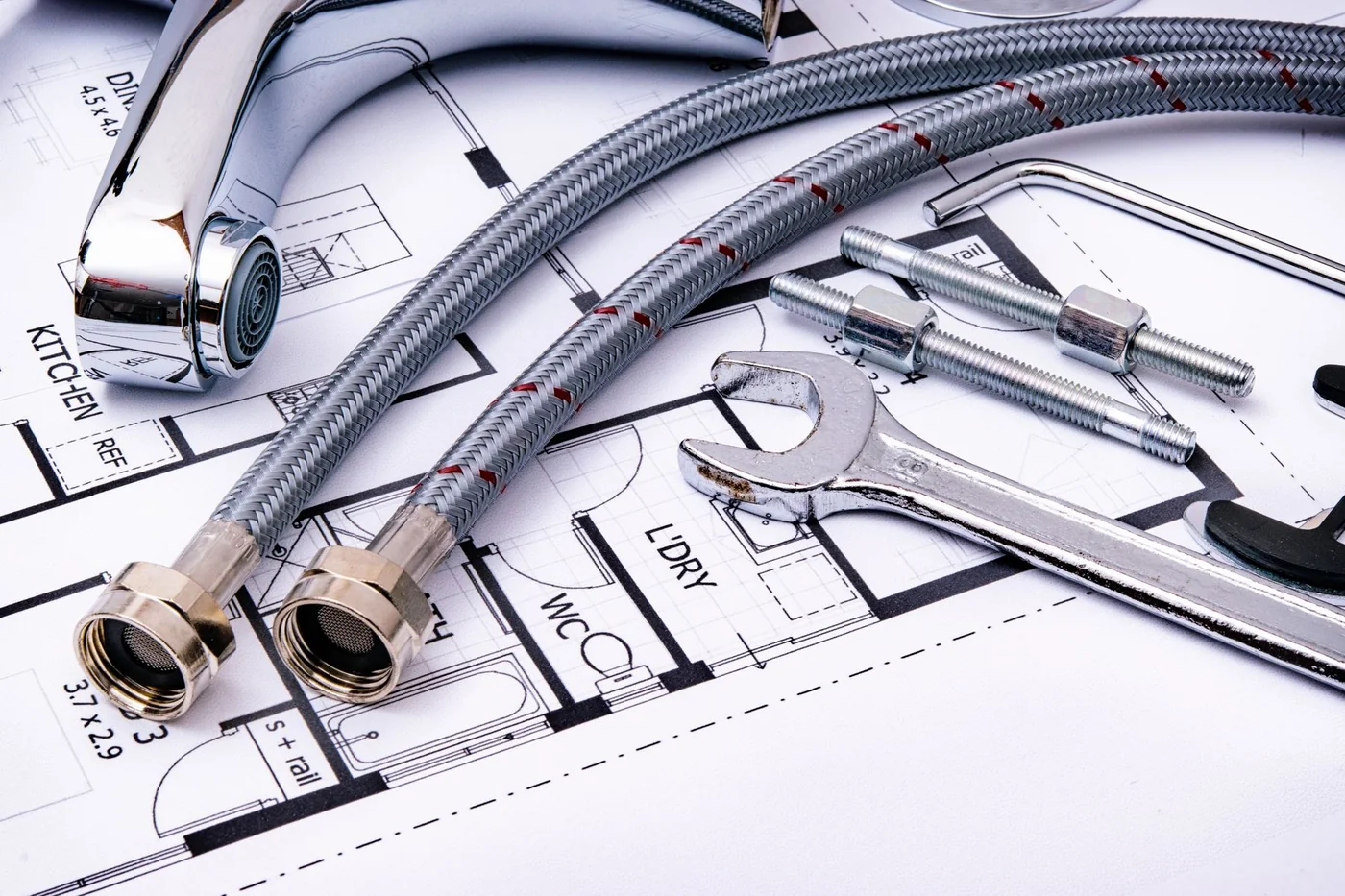 Plumbing fittings, a faucet, and a pipe wrench on a plan